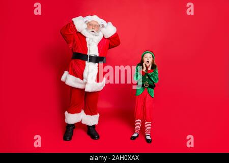 Voller Körper Foto der erstaunt Santa Claus mit seiner Enkelin in Grün elf Kostüm scream omg siehe Noel unfassbares Wunder tragen Gürtel Brillen Stockfoto