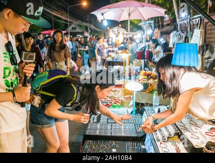 Chiang Mai, Thailand - Dezember 5, 2017: Junge asiatische Touristen Schmuck bei der Saturday Night Bazaar wählen. Ein traditioneller Markt jede Woche in Chiang Mai, Nordthailand. Stockfoto