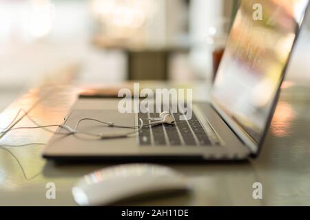 Close-up Paar weiße Kopfhörer auf der Tastatur Laptop in geringer Tiefenschärfe. Stockfoto