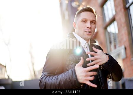 Mann zu Fuß in der Stadt gegen den Hintergrund der Gebäude am Tag. Sonnenlicht Wirkung Stockfoto