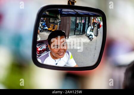 Ein Tuk Tuk Fahrer Refected In seinem Rückspiegel, Phnom Penh, Kambodscha. Stockfoto