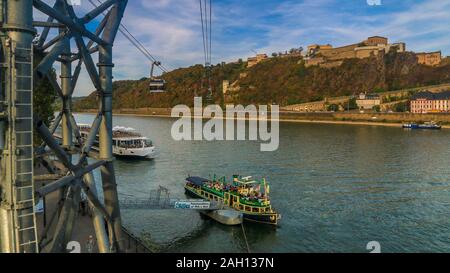 Schöne Sicht auf die Festung Ehrenbreitstein am östlichen Ufer des Rheins, die Fahrgastschiffe auf dem Wasser und die Seilbahn überquert den Fluss auf einer... Stockfoto