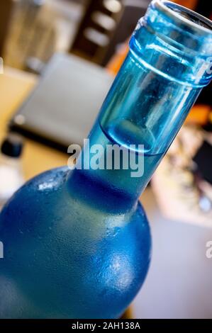 Detailansicht der Hals einer blauen Flasche Wasser auf einem Tisch in einer Bar nach Tag Stockfoto