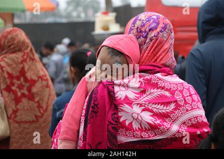 Winterkollektion DC 21de2019 kuril Dhaka Bangladesch.eine ältere Frau hält das Baby in ihren Armen und wickelt es mit einem Laken um, um es vor der Kälte zu schützen Stockfoto