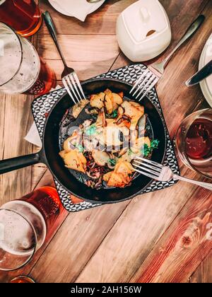 Eine Menge Bier. Bratkartoffeln in der Pfanne in der Mitte der Tabelle. Flatlay, Ansicht von oben, für instagram Erntegut Stockfoto