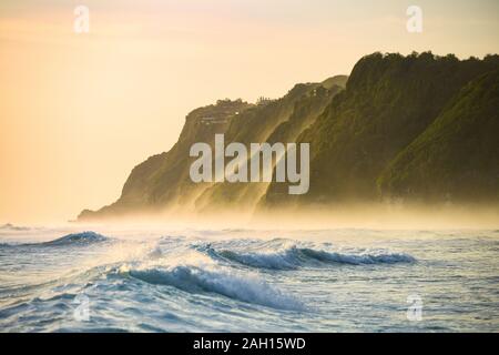 (Selektive Fokus) einen atemberaubenden Blick auf die Melasti Beach mit seinem Felsen durch eine raue Meer bei einem schönen Sonnenuntergang, South Bali, Indonesien getaucht. Stockfoto