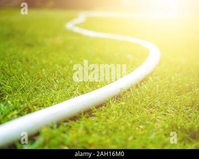 Weiß Bewässerung Schläuche auf grünem Rasen. Tag Sommer. Sonnig Stockfoto