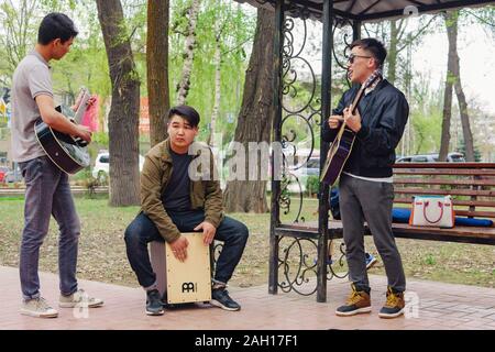 Bischkek, Kirgisische Republik - 14. APRIL 2018: Festival Musik Band. Freunde spielen auf Schlaginstrumente im City Park. Bank und Bäume in der backgro Stockfoto