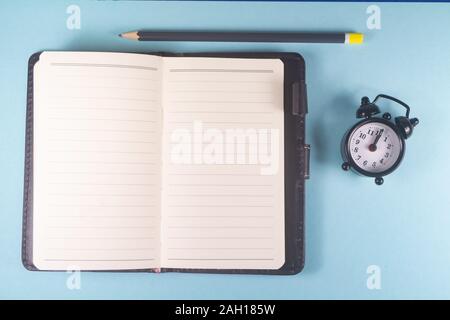 Bleistift, öffnen Notebook und schwarzen Wecker Stockfoto