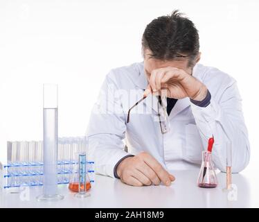 Müde junge Arzt versucht zu konzentrieren. Halten Sie den Kopf und Brillen sitzen im Labor. Foto auf weißem Hintergrund. Stockfoto