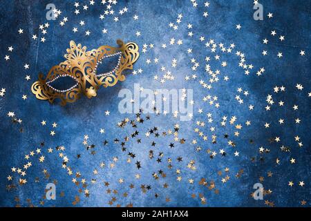 Golden Karneval Maske und Konfetti mit goldenen Sternen auf blauem Hintergrund. Ansicht von oben, kopieren. Karneval Party Feier Konzept. Stockfoto