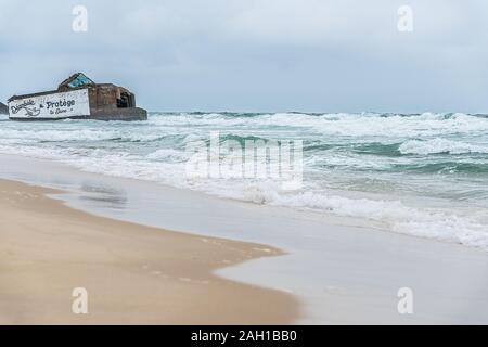 Beton Bunker aus Kriegszeiten Vergangenheit in Shorebreak auf Französisch Strand Stockfoto