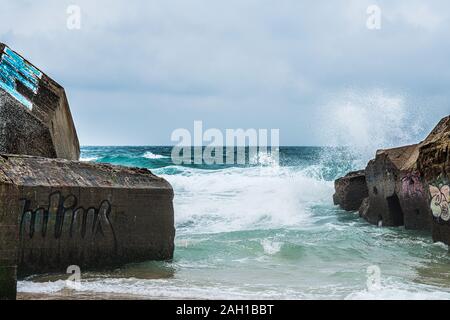 Beton Bunker aus Kriegszeiten Vergangenheit in Shorebreak auf Französisch Strand Stockfoto