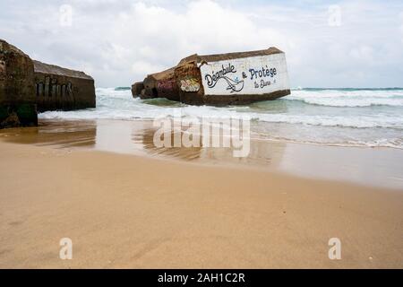 Beton Bunker aus Kriegszeiten Vergangenheit in Shorebreak auf Französisch Strand Stockfoto