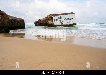 Beton Bunker aus Kriegszeiten Vergangenheit in Shorebreak auf Französisch Strand Stockfoto