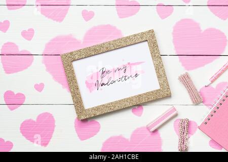 Mockup Bilderrahmen für Valentines Tag Konzept. Blick von oben auf die Mock up Bilderrahmen mit Handwerk Dekoration und Notebook auf weißem Holz mit rosa Herzen painte Stockfoto