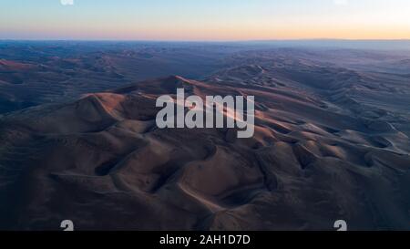 Luftaufnahme von der Bildung von hohen Sanddünen und tiefen Tälern mit klarem Himmel bei Sonnenaufgang in der Dasht e Lut Wüste Stockfoto