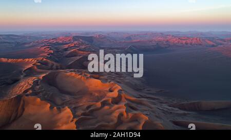 Luftaufnahme von der Bildung von hohen Sanddünen und tiefen Tälern mit klarem Himmel bei Sonnenaufgang in der Dasht e Lut Wüste Stockfoto