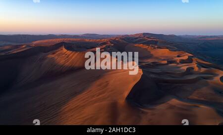 Luftaufnahme von der Bildung von hohen Sanddünen und tiefen Tälern mit klarem Himmel bei Sonnenaufgang in der Dasht e Lut Wüste Stockfoto