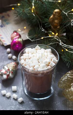 Kakao mit Marshmallows auf dem Hintergrund von Vintage-Weihnachtsspielzeug und alten Buchstaben und Karten. Stockfoto