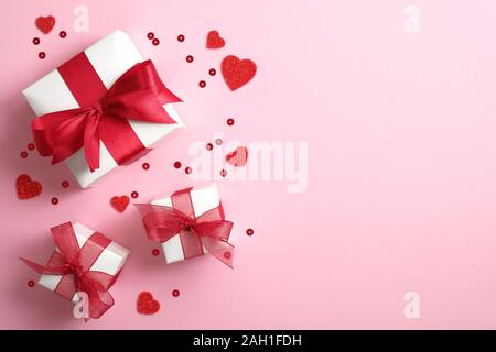Geschenkboxen verpackt Weißbuch mit roter Schleife und Valentines Herz auf rosa Hintergrund. Flach, Ansicht von oben. Banner oder Grußkarte Mockup für Va Stockfoto