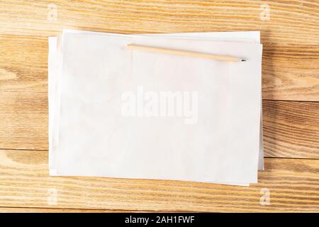 Blatt Papier liegen auf Holztisch. Rechteckige weiße Altes Papier mit Bleistift Stack. Strukturierte natürliche Holz- Hintergrund. Jahrgang kopieren Platz für Stockfoto