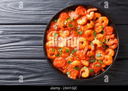 Garnelen mit Knoblauch und Kräutern in Tomatensauce close-up in einem Teller auf dem Tisch. Horizontal oben Ansicht von oben Stockfoto