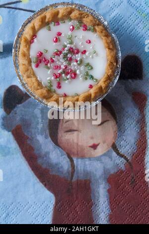 Herr Kipling festliche Bakewells bakewell tart überaus guten Kuchen auf Serviette mit Girl holding hands up Stockfoto