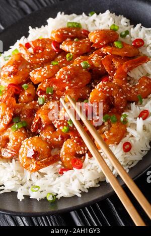 Asiatische Chili Knoblauch Garnelen Garnelen mit Reis Beilage close-up in einem Teller auf dem Tisch. Vertikale Stockfoto