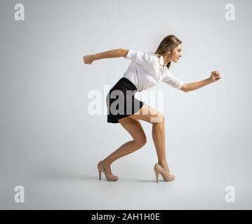 Ich kann nichts tun. Glückliche Frau im Büro Kleidung Vorbereitung auf Grau studio Hintergrund zu laufen. In motion Geschäftsfrau, Aktion. Für Sport, neue Aktivität. Sport, Fußball, gesunden Lebensstil. Stockfoto