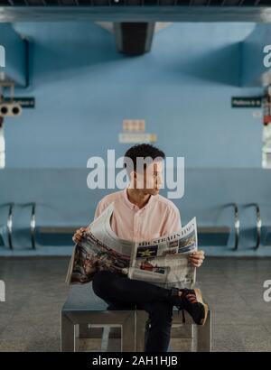 Singapurische männliche in rosa Shirt, die Straits Times Zeitung in Queenstown MRT, Rechtsblick, Pendler Lifestyle, Daily Reading, öffentliche Verkehrsmittel Stockfoto