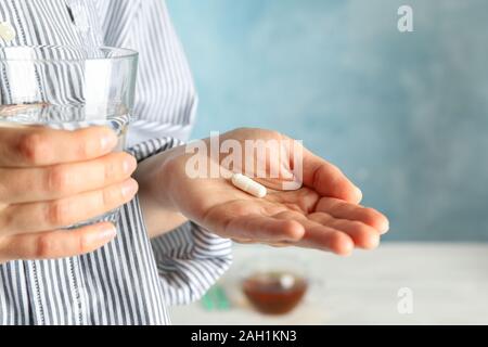 Frau, die die Pille und Glas Wasser vor blauem Hintergrund, Platz für Text Stockfoto