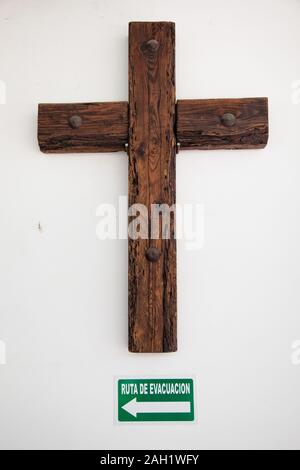 Kreuz oder Kruzifix mit fluchtweg Schild an Betonwand. Konzept für Zweifel an der Religion Stockfoto