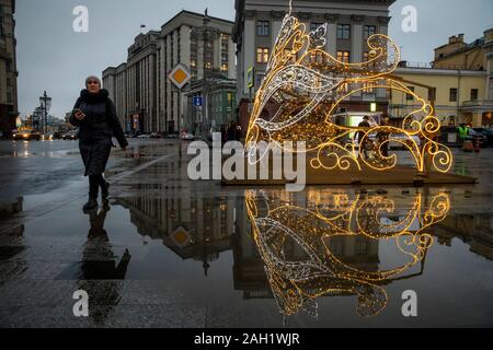 Moskau, Russland. 18. Dezember, 2019 Eine Frau geht Vergangenheit Dekorationen für das kommende Neue Jahr und Weihnachtszeit auf eine extrem warme Winter Tag, am Theaterplatz installiert auf dem Hintergrund der Staatsduma der Russischen Föderation, in der Innenstadt von Moskau, Russland. Stockfoto