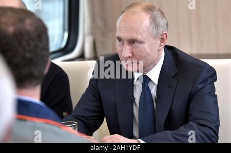 Taman, Russland. 23. Dezember, 2019. Der russische Präsident Wladimir Putin, rechts, erfüllt der Arbeitnehmer beim Reiten auf der neu eröffneten Eisenbahn auf der Krim-Brücke über die Straße von Kertsch verbinden auf der Krim, Krasnodar Dezember 23, 2019 in Taman, Russland. Die 19 km lange Brücke ist die längste in Europa und war fünf Jahre nach Russland im Anhang das Schwarze Meer Halbinsel. Credit: Aleksey Nikolskyi/Kreml Pool/Alamy leben Nachrichten Stockfoto