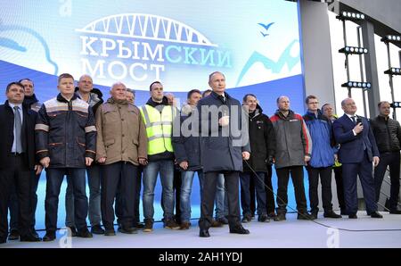 Taman, Russland. 23. Dezember, 2019. Der russische Präsident Wladimir Putin, Mitte, Adressen Arbeitnehmer während der Eröffnungsfeier für die Krim-Brücke Eisenbahnverbindung über die Straße von Kertsch verbinden auf der Krim, Krasnodar Dezember 23, 2019 in Taman, Russland. Die 19 km lange Brücke ist die längste in Europa und war fünf Jahre nach Russland im Anhang das Schwarze Meer Halbinsel. Credit: Aleksey Nikolskyi/Kreml Pool/Alamy leben Nachrichten Stockfoto