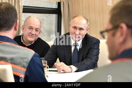 Taman, Russland. 23. Dezember, 2019. Der russische Präsident Wladimir Putin, Mitte, erfüllt der Arbeitnehmer beim Reiten auf der neu eröffneten Eisenbahn auf der Krim-Brücke über die Straße von Kertsch verbinden auf der Krim, Krasnodar Dezember 23, 2019 in Taman, Russland. Die 19 km lange Brücke ist die längste in Europa und war fünf Jahre nach Russland im Anhang das Schwarze Meer Halbinsel. Credit: Aleksey Nikolskyi/Kreml Pool/Alamy leben Nachrichten Stockfoto