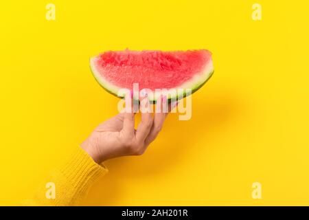 Hand hält Wassermelone Schicht über gelben Hintergrund. Sommer Konzept. Stockfoto