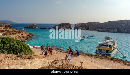 Blick auf die Blaue Lagune und Cominoto Insel Comino Insel. Menschen entspannen in die Blaue Lagune, die mit Fähren und Boote in türkisfarbenem Wasser. Stockfoto