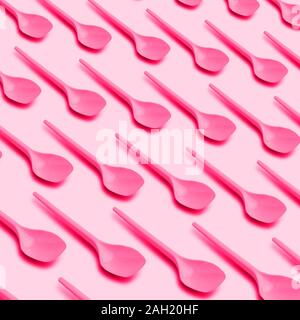 Flach Foto von rosa Plastiklöffel aus recycelbarem Kunststoff. Kreative Draufsicht Muster. Auf rosa Hintergrund. Stockfoto
