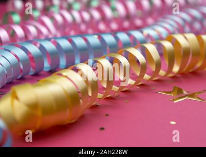Karneval festliche Curling bunte Papier streamer Dekorationen auf rosa Hintergrund Stockfoto