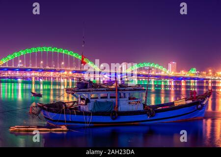 Vietnamesische Fischerboot auf den Fluss Han und Dragon Brücke, wie vom Ufer aus in der Nacht Da Nang, Vietnam beobachtet Stockfoto