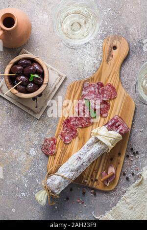 Italienische Salami auf Holzbrett mit Käse und Oliven Stockfoto