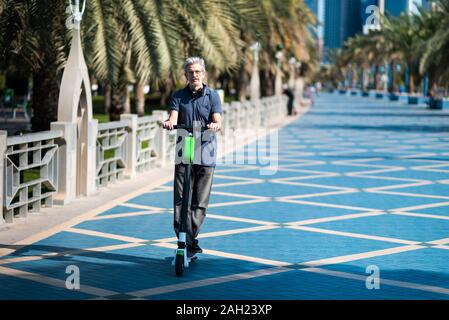 Senior mit elektrischer Roller für den Transport in einer modernen Stadt Umgebung Stockfoto