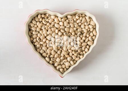 Ungekochte schwarze gefärbte Peas in Herzform Stockfoto