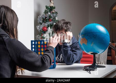 Gelangweilte Geschwister spielen Connect Four am Weihnachtstag Stockfoto