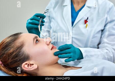 Dame mit Pflaster auf der Nase, Arzt Patienten Prüfung Gesicht nach der plastischen Chirurgie. Stockfoto