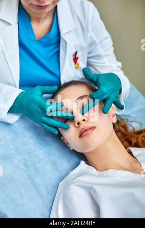 Dame mit Pflaster auf der Nase, Arzt Patienten Prüfung Gesicht nach der plastischen Chirurgie. Stockfoto