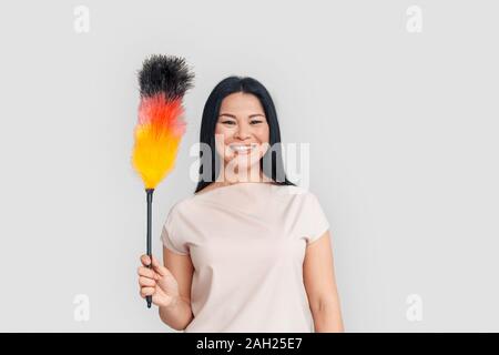 Freestyle. Asian woman standing isolated on white with duster smiling cheerful Stockfoto