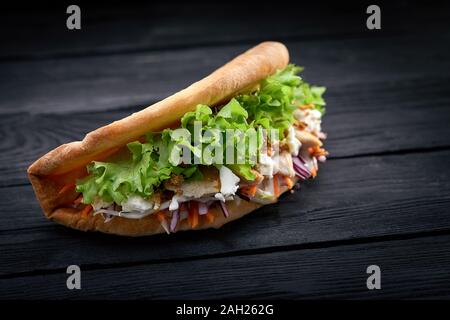 Döner Kebab - gebratenes Hühnerfleisch mit Gemüse in pita Brot auf schwarzem Holz- Hintergrund Stockfoto